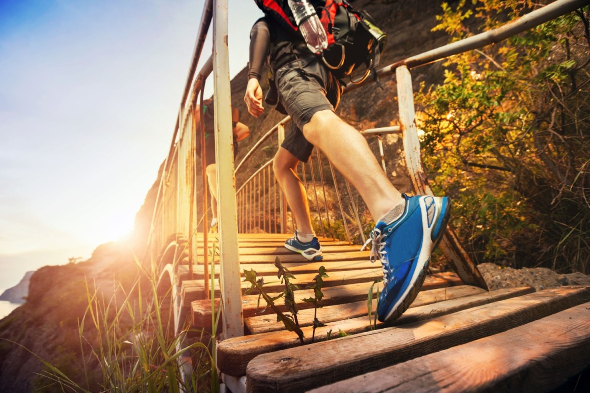 man-walking-accross-a-bridge-with-the-sun-shining-in-the-background.jpg